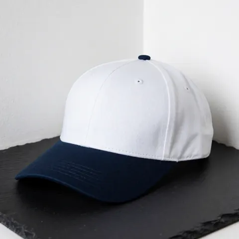 White and navy blue baseball cap on dark slate surface, ideal for embroidery customization