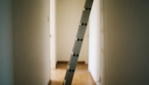 Aluminum ladder leaning against a hallway wall with a blurred background, suitable for overlaying text.