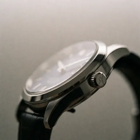 Close-up of a luxury watch featuring a sapphire crystal face and black leather strap against a neutral background with professional lighting highlighting its polished finish.