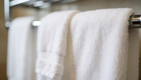 Soft white towels hanging on a bathroom rack with a blurred background and diffused light, ideal for text or logos