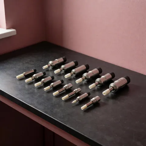 New piezoelectric stove igniters arranged on a black countertop against a pink wall with soft lighting from the upper left.
