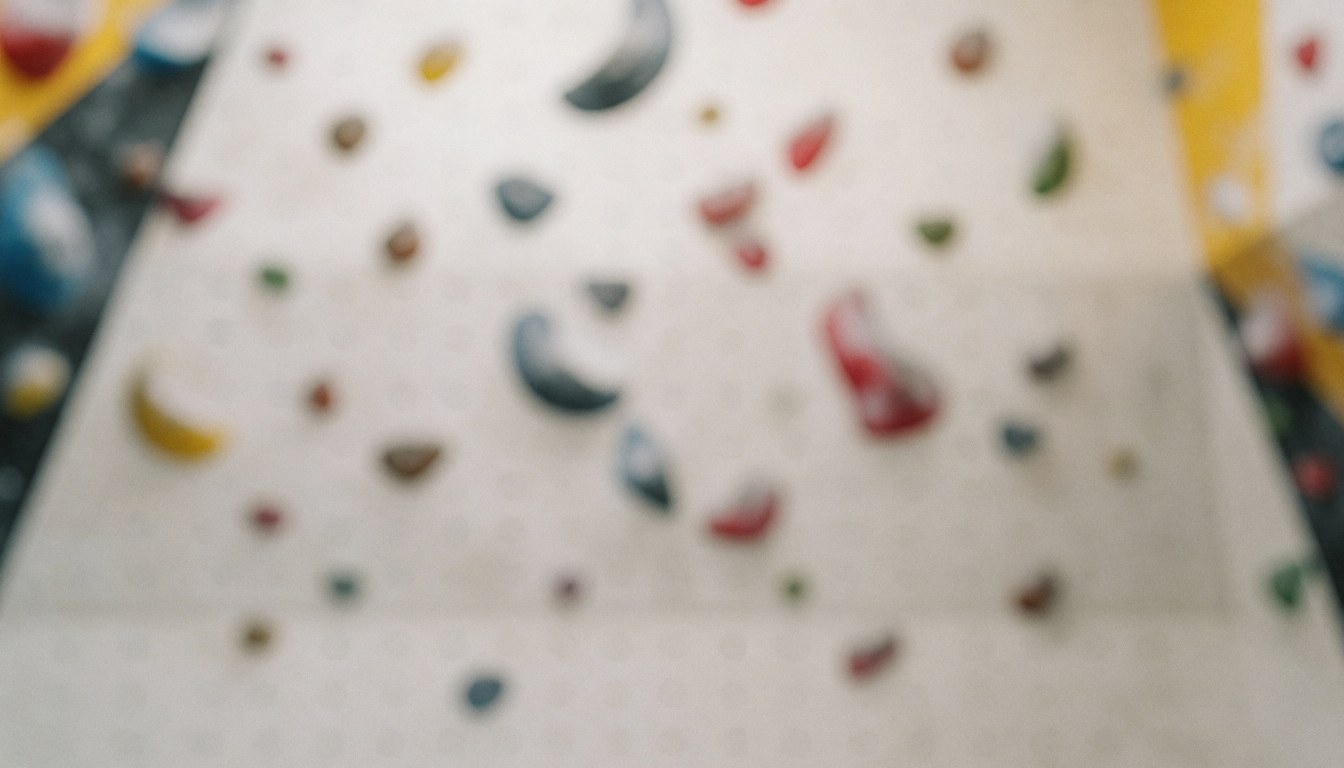 Soft-focus background of an indoor climbing gym wall featuring colorful handholds and neutral lighting, suitable for text overlays and graphic design projects.