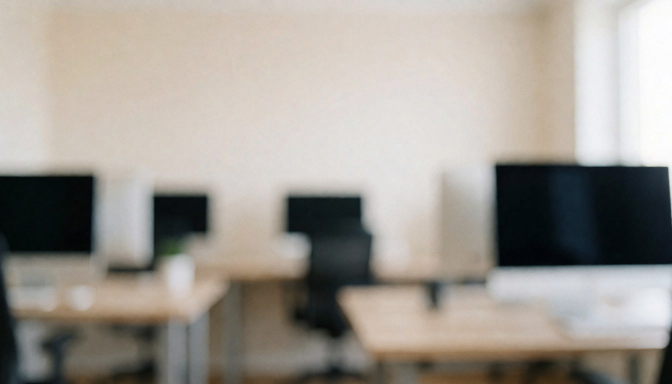 Softly blurred professional photo editing studio workspace featuring desks and computer monitors with neutral lighting, ideal for text overlay.