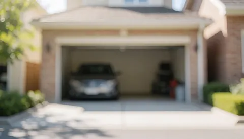 Softly blurred background of a home garage featuring a parked car, brick walls, vegetation, and natural lighting, ideal for text overlay.