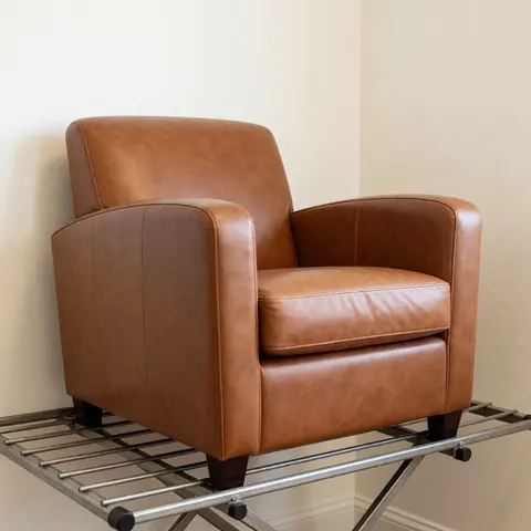 Refurbished brown leather chair sitting on a metal drying rack against cream walls with soft professional lighting