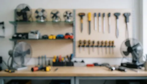 Out of focus repair shop background featuring shelves, hanging tools, and fans on a table for text overlay