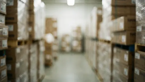 Blurred warehouse aisle with stacked flooring boxes, serving as a professional background for business text overlays.