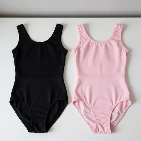 Flat lay of pink and black dance leotards on a white surface showing fabric texture and elasticity with soft lighting