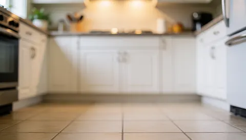 White kitchen cabinets and tiled floor background with warm lighting, suitable for text or commercial logos.