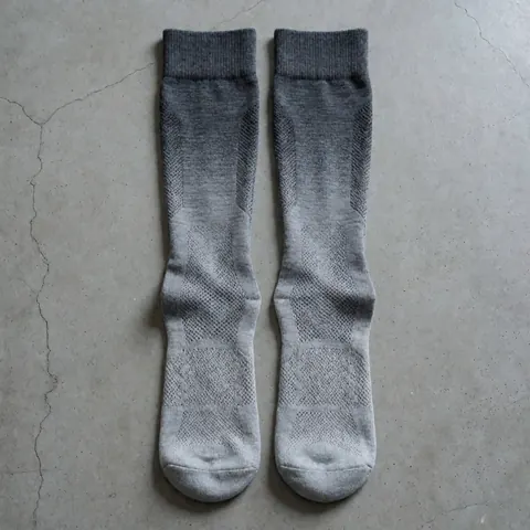 Close-up of gray gradient athletic socks with visible mesh fabric lying on a concrete surface for sports training