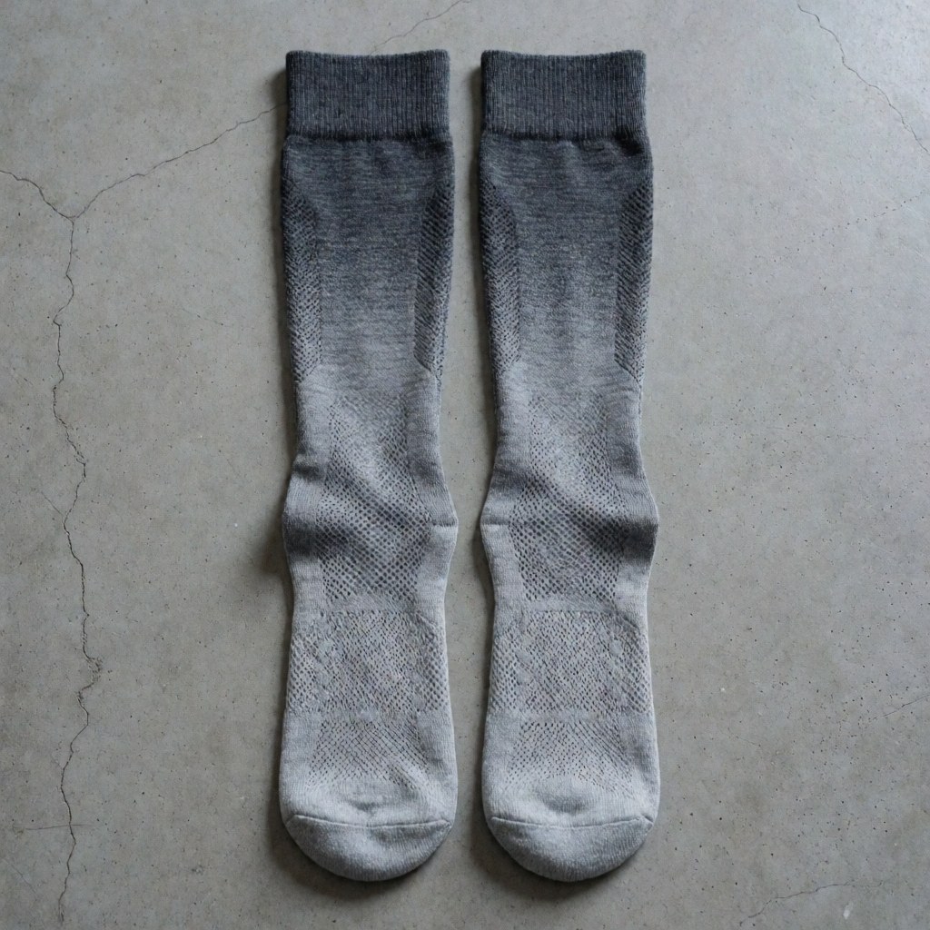 Close-up of gray gradient athletic socks with visible mesh fabric lying on a concrete surface for sports training