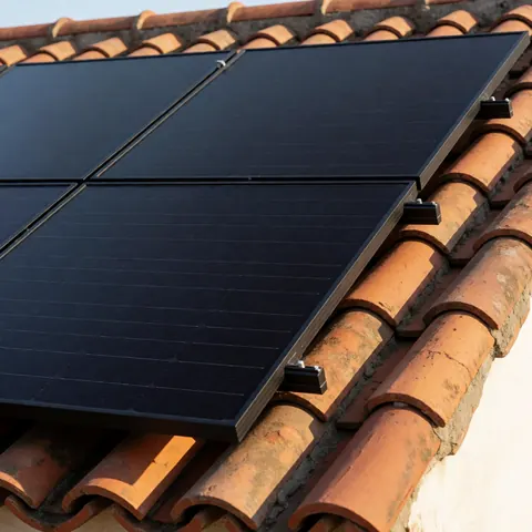 Close-up of a black solar panel securely mounted on a curved terracotta tile roof under bright sunlight, highlighting ceramic texture and repair context.