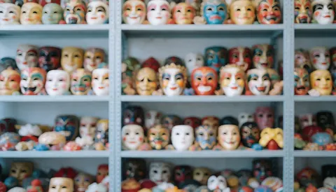 Blurred colorful theater masks on shelves with soft neutral lighting, ideal for text background and graphic design.