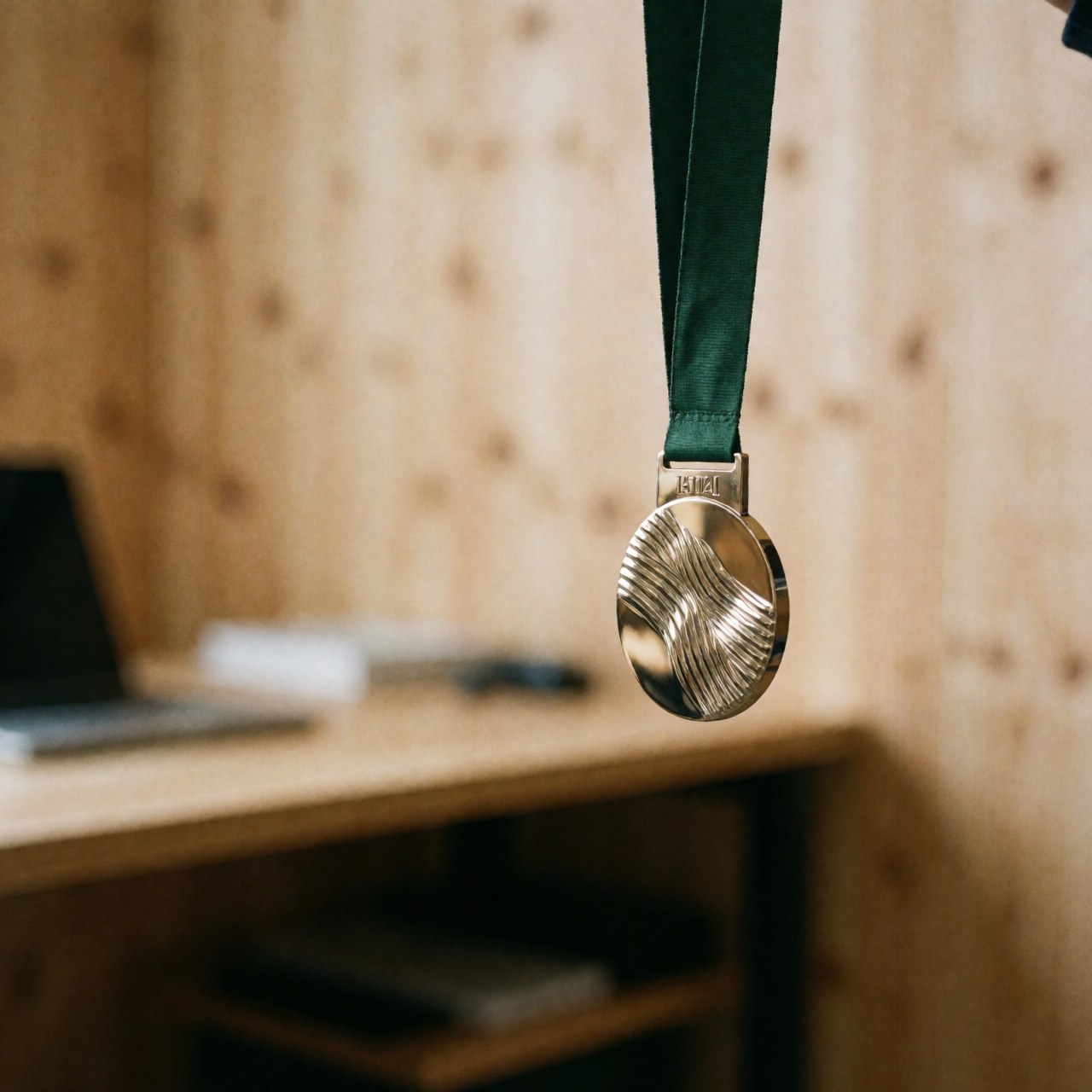 Mountain medal hanging from green ribbon in an office with wooden walls, suitable for promoting mountain bike coaching services.