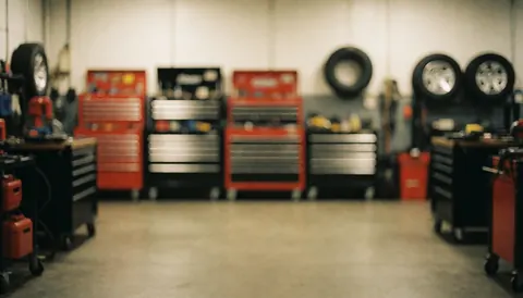 Out of focus RV repair shop background featuring red and black toolboxes, tires, and a concrete floor, suitable for text overlay.