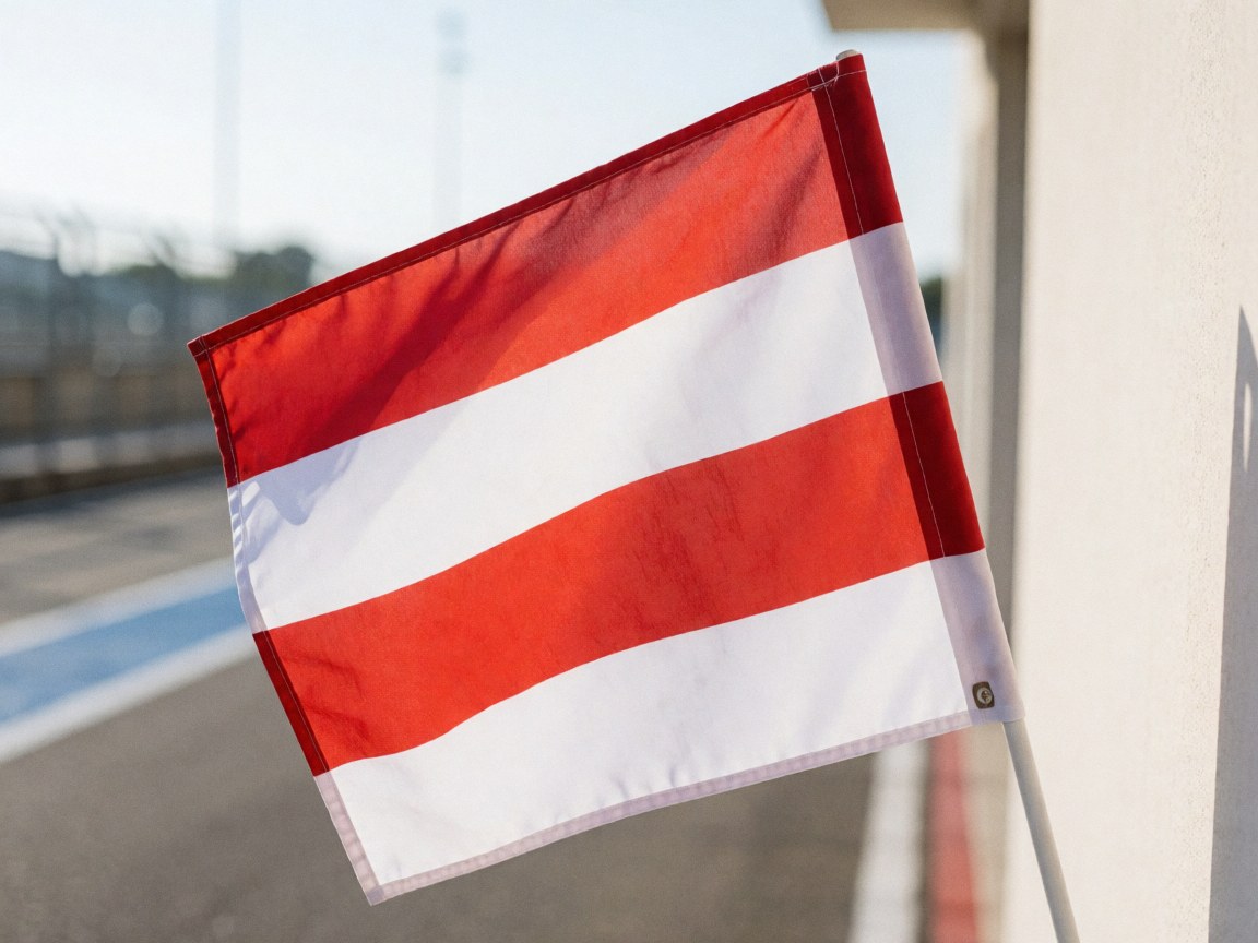 Red and white pit lane flag on a race track with blurred asphalt and barriers in the background under bright daylight