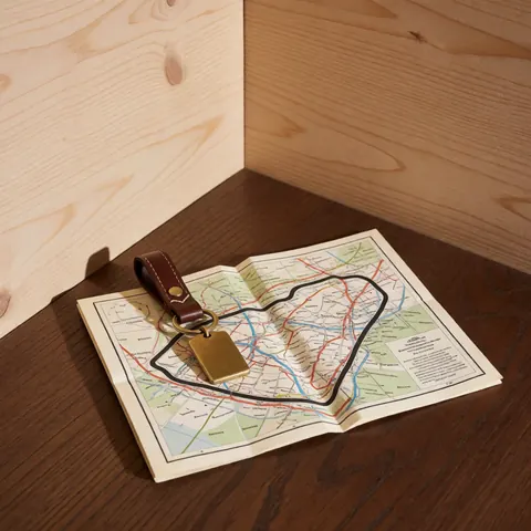 Bronze car key with leather strap on folded circuit map over dark wood surface with light wood walls
