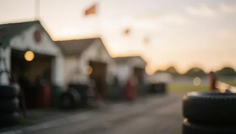Stacked tires in a blurred motorsport pit lane with garages and golden hour light, ideal for business text backgrounds
