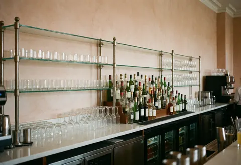 A party bar setup featuring arranged liquor bottles and glasses against terracotta walls, creating a clean and professional atmosphere.
