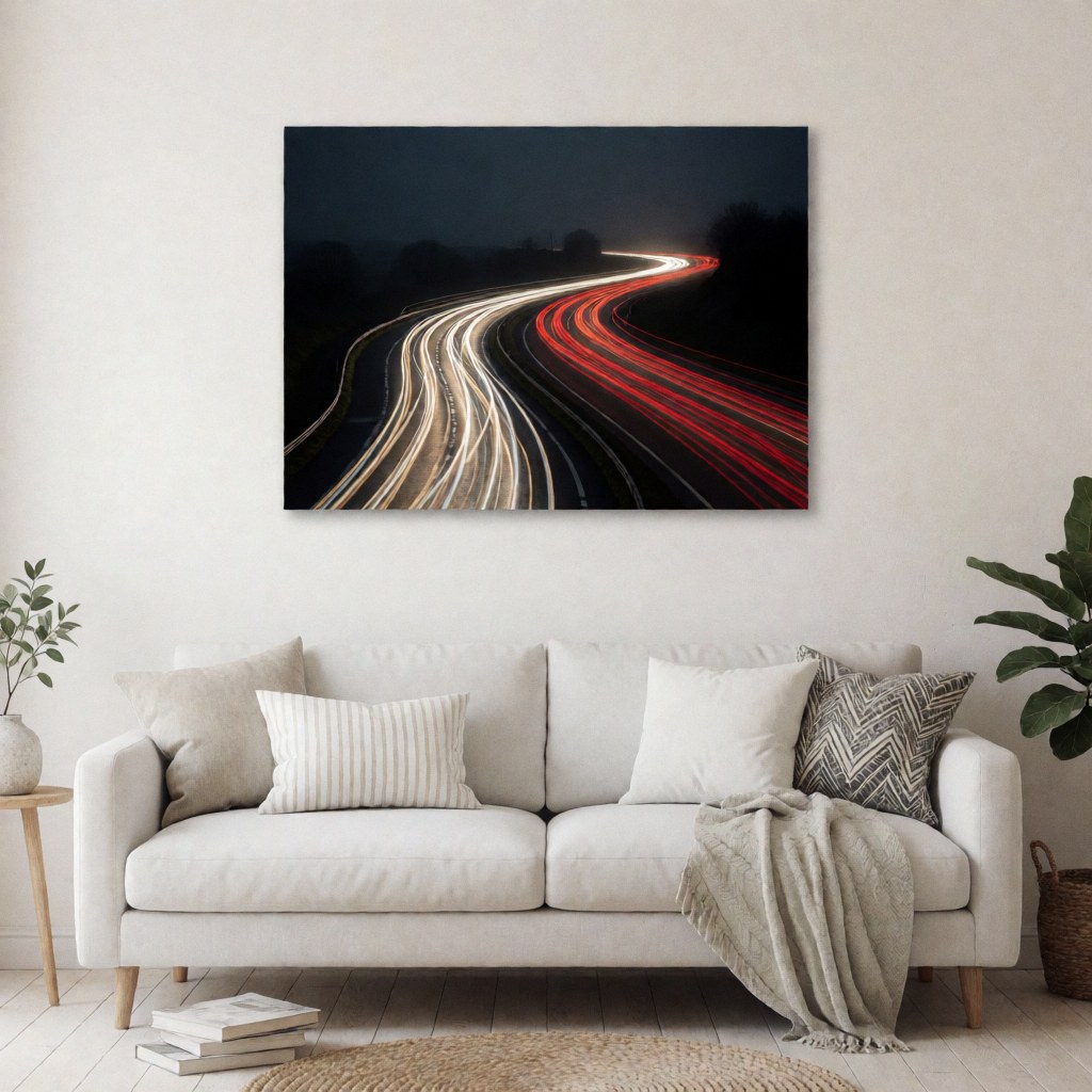 Artistic long exposure photo showing red and white car light trails on a curved road under a dark sky, displayed as wall decor in a home interior