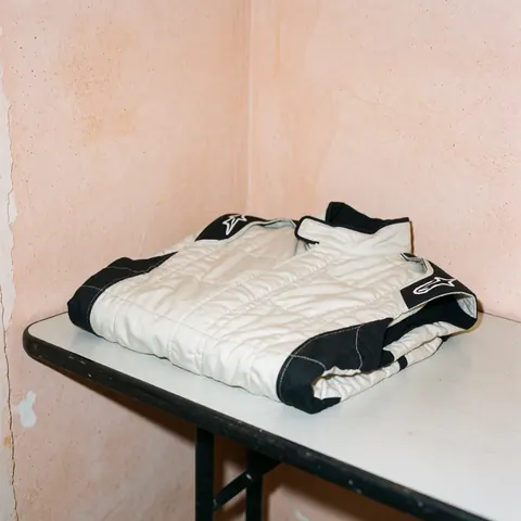 Folded black and white racing jacket on white table with terracotta walls and visible texture