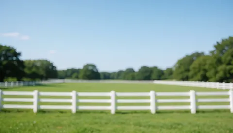 Green grass with white fences and blue sky, ideal for text about rural tranquility and animal welfare