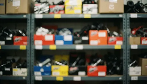 Out of focus background of metal shelves holding colorful boxes containing motorcycle spare parts, suitable for text overlay