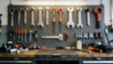 Blurred motorcycle repair shop background featuring tools hanging on a pegboard, work tables, and soft lighting, ideal for text overlay.