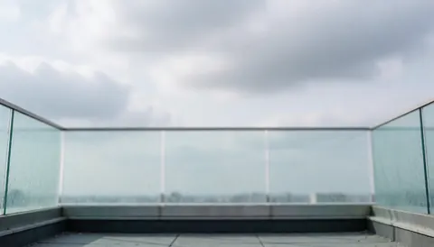 Modern terrace background with glass railing and cloudy sky, ideal for window cleaning services. Text or logo can be placed on top.