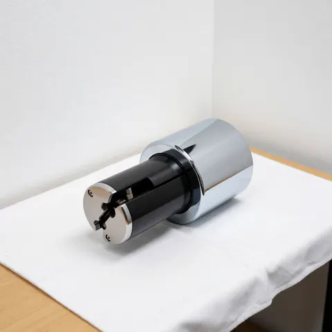 Chrome-finished high security lock cylinder with black core on white fabric, clinical lighting, white walls, lock repair product