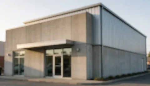 Out of focus industrial building exterior featuring concrete and metal walls illuminated by soft warm sunset light, suitable for commercial text overlay.