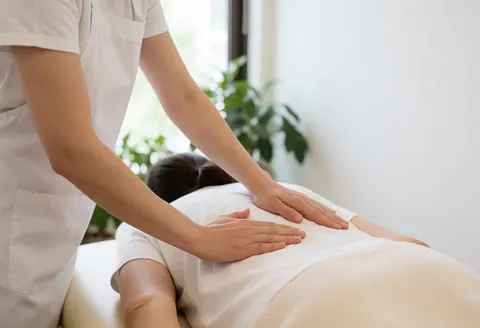 Therapist hands performing deep tissue massage in a bright clinic with natural light and relaxing atmosphere