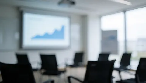 Professional meeting room background featuring black chairs and a projected screen displaying analysis charts, suitable for strategy and planning text overlays.