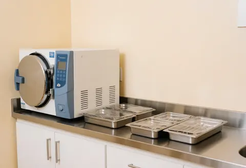 Sterilization chamber with sealed metal trays on a stainless steel counter in a clean clinical room