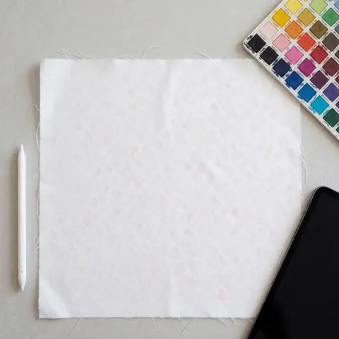 White textile featuring a digital print pattern displayed alongside a color palette and stylus on a light gray background with even lighting.