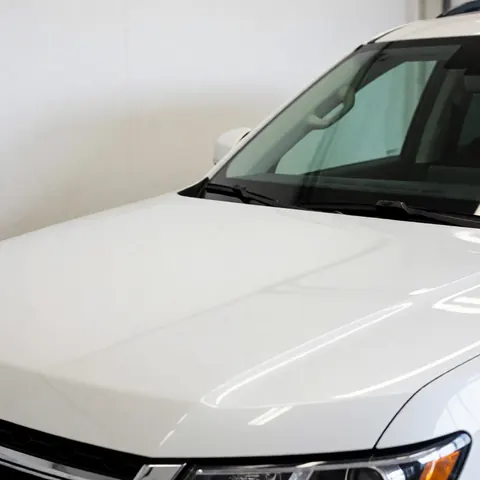 Flawless white SUV hood with light reflections in a workshop, no tools visible, polished and clean surface