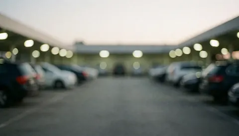 Professional blurred background of parked cars and bright lights in a parking lot, suitable for business text overlays