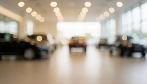 Blurred car dealership interior with warm lights and reflections on polished floor, ideal for text overlay