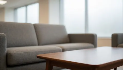 Textured gray sofa and wooden table in a professional sales room with diffused window light, ideal for commercial text backgrounds