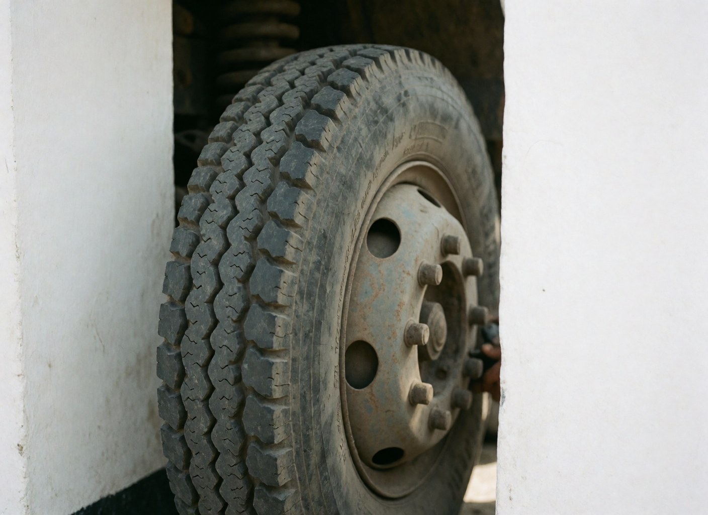 Close-up of a truck wheel featuring tire tread, white sidewalls, and metal and rubber details for logistics and transport businesses