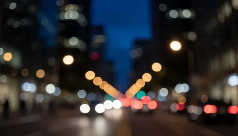 Blurred night city background with blue and black tones from car and building lights, suitable for transport service text overlays