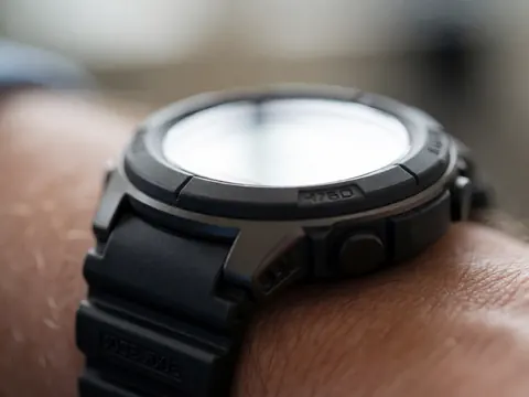 Macro shot of a digital watch with bright backlight, showing bezel and black strap details with selective focus on the device.