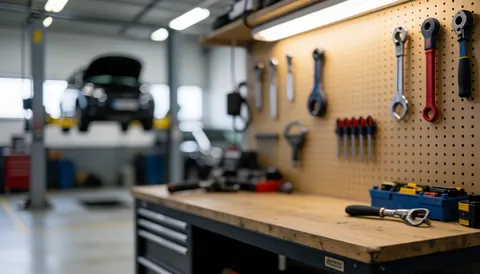 Blurred automotive workshop background featuring a pegboard wall with hanging tools and an elevated car, ideal for business text overlays