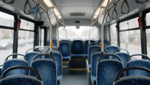 Empty public bus interior featuring blue seats and metal handrails with a blurred background suitable for text or graphic design