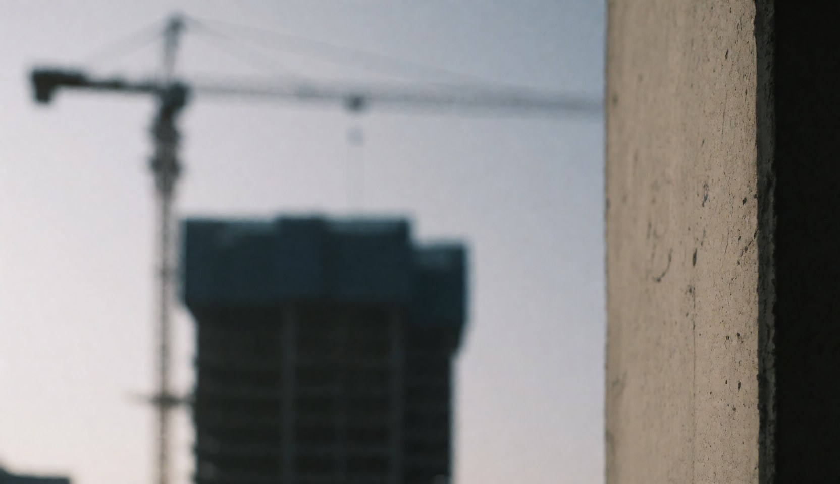 Blurred construction site background featuring a crane silhouette against a concrete texture, suitable for business text overlays