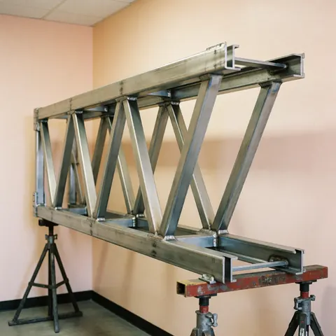 Steel structure with metal crossbeams and supports in an industrial workshop with beige walls and uniform lighting.