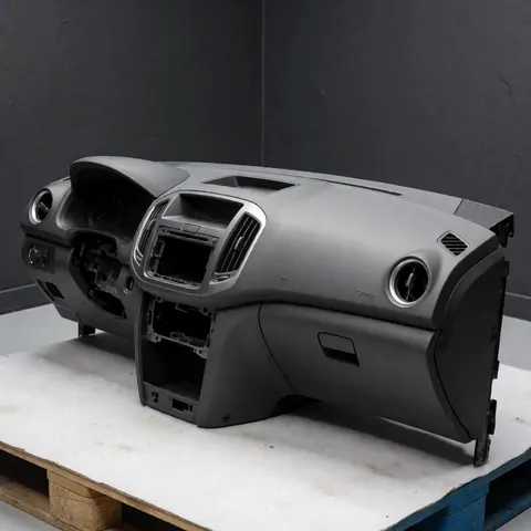Clean and intact vehicle dashboard component resting on a wooden pallet in a workshop with a gray background