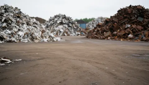Mounds of rusty and non-rusty scrap metal on compacted dirt ground, suitable as a background for vehicle recycling service text.