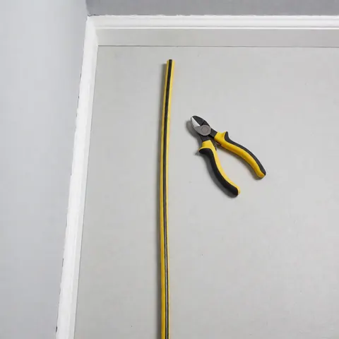 Top view of yellow and black RYY-U electrical cable and a wire cutter on a light gray surface for residential electrician product display