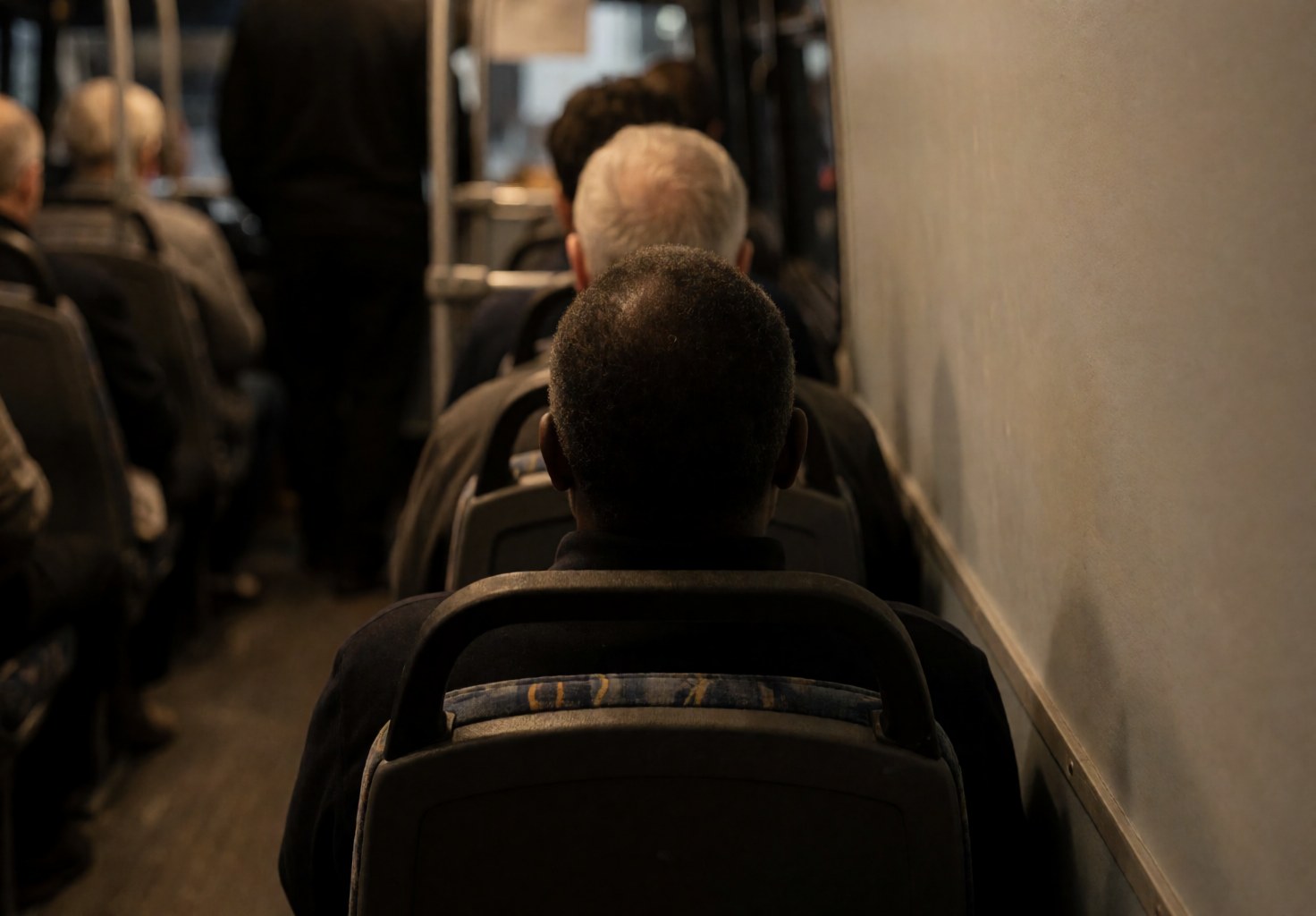 A passenger sleeps in a tour bus seat with warm lighting and a relaxed atmosphere while other passengers are visible in the background.
